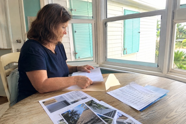 A Florida homeowner organizes roof photos and documents for a home-hardening grant application