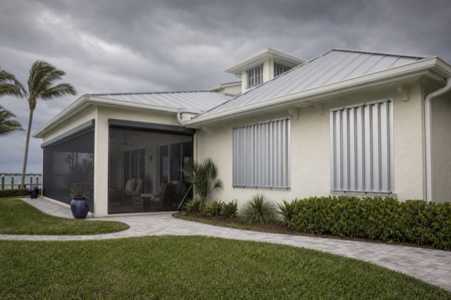 A coastal home with patio screening and closed metal storm shutters