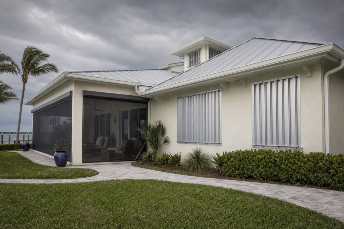 A coastal home with patio screening and closed metal storm shutters