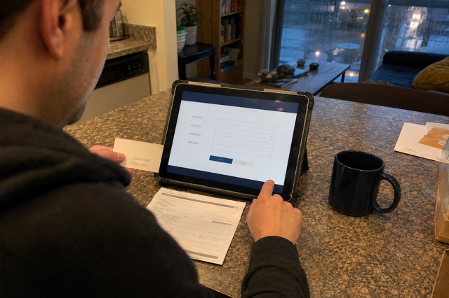 A homeowner compares a contractor estimate with a state license lookup on a tablet