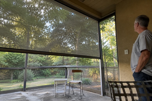 A homeowner observes a lowered motorized patio screen from a safe distance