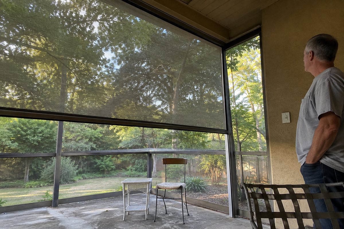 A homeowner observes a lowered motorized patio screen from a safe distance