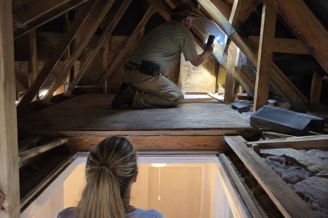 A home inspector photographs a roof-to-wall connection from a stable attic walkway